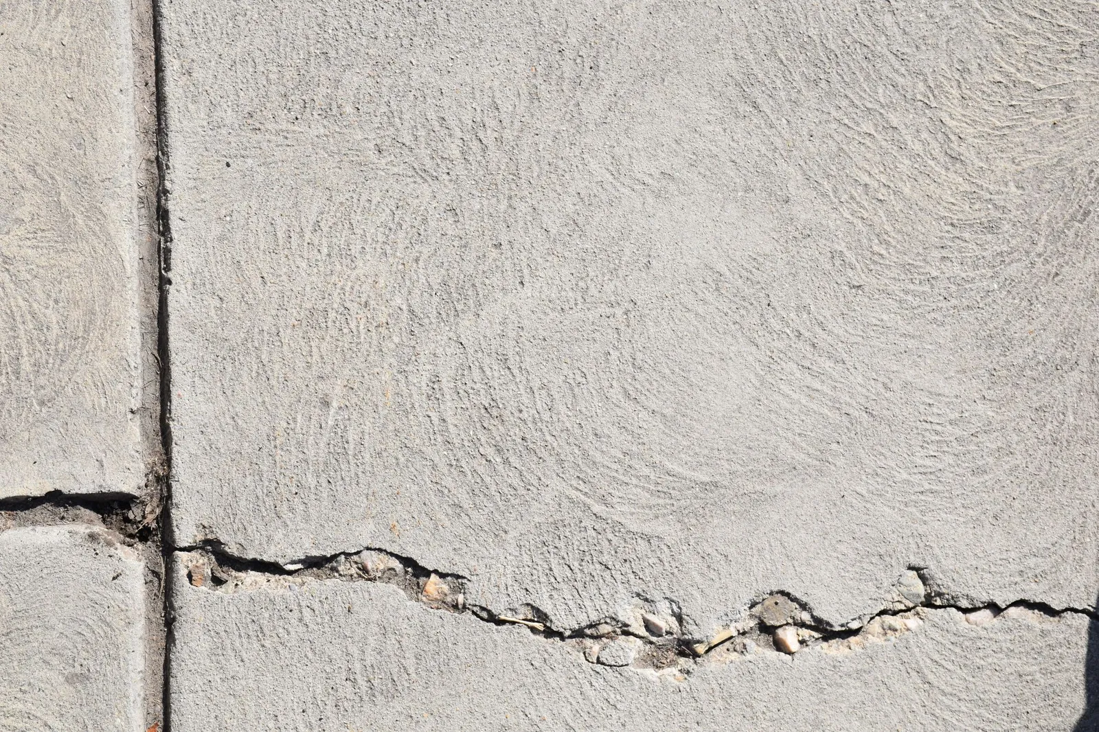 Close-up view of a cracked concrete surface with distinct textures in Logan, Utah.